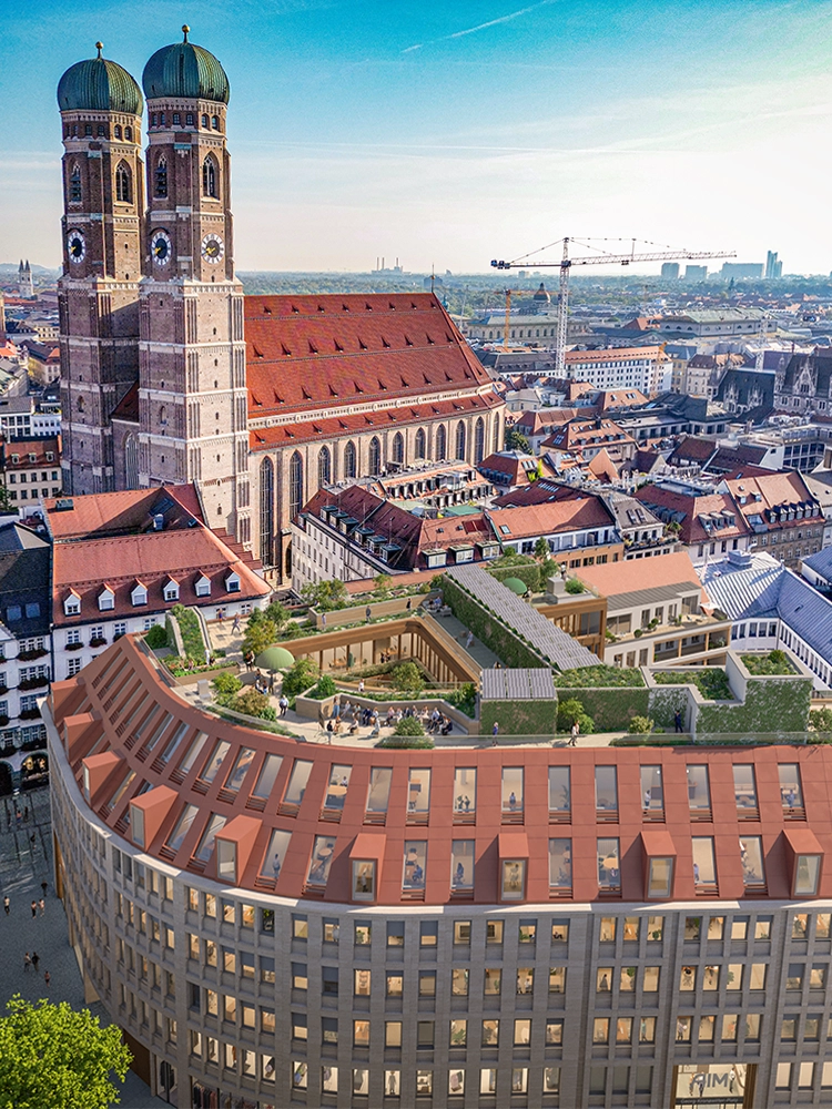 Die Frauenkirche in München erhebt sich über einem modernen Gebäude mit begrüntem Dachgarten unter klarem Himmel.